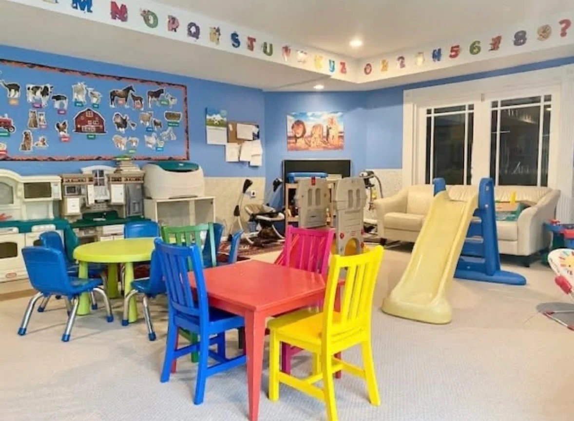 Bright daycare playroom with tables and indoor play equipment